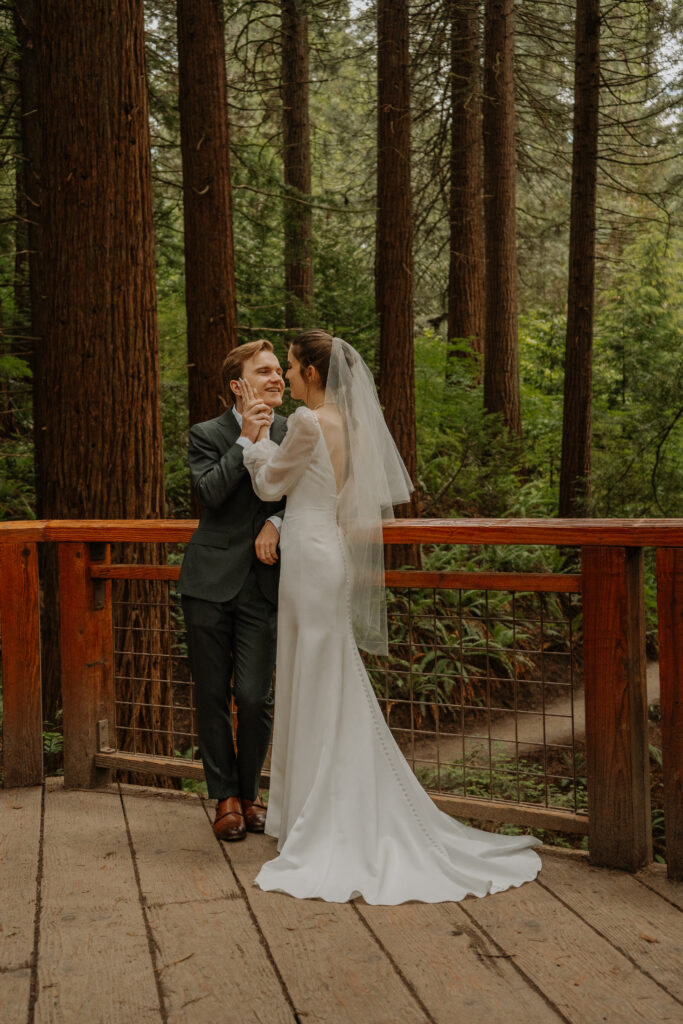 A bride and groom embracing each other in a redwood forest
